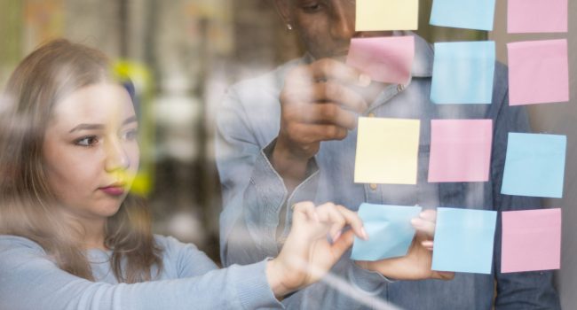 front-view-man-woman-putting-sticky-notes-office-window